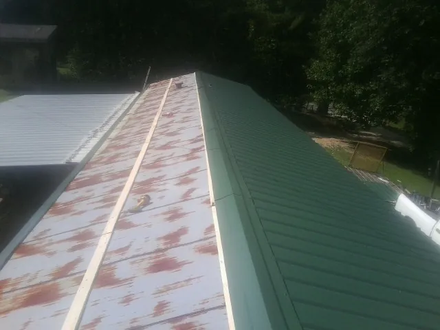 Old rusted panels beside newly installed green metal roofing — Wind Damage Roof Repair by Roofing Brothers in Winter Haven