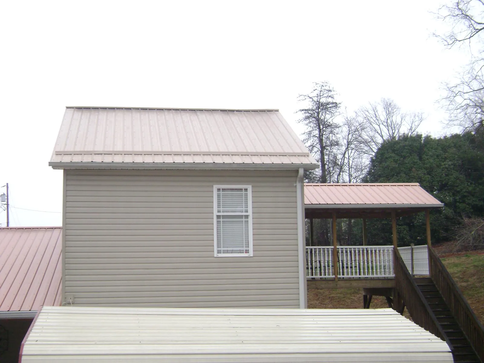 Tan metal roofs on a two story addition and attached porch, from a Roof Replacement job in Winter Haven