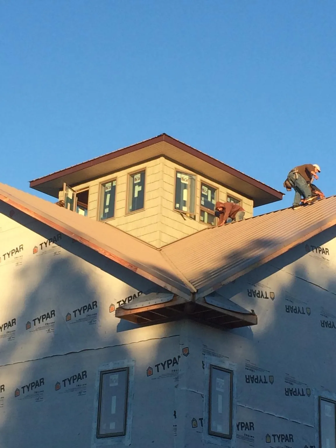 Roofers working around a rooftop cupola on a new metal roof at sunset — Roof Waterproofing in Winter Haven by Roofing Brothers